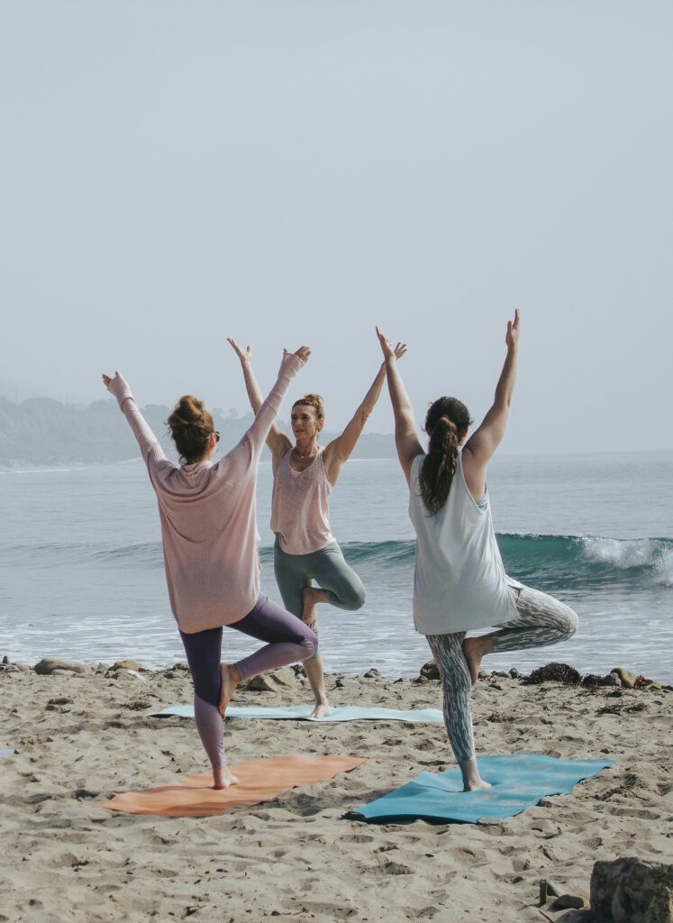 People doing yoga on the beach